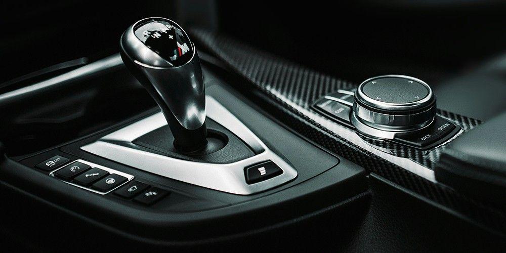 Close-up of a BMW gear shift lever and control dial in a modern interior.